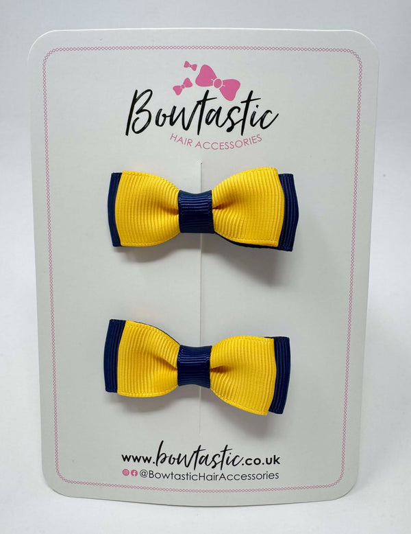 Two hair bows in yellow gold and navy colors, attached to a white backing card with the brand name 'Bowtastic' at the top.