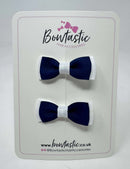Two navy blue and white hair bows on a 'Bowtastic' branded card.